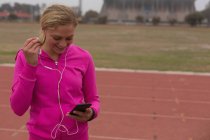Спортсмен слушает музыку на мобильном телефоне на беговой дорожке — стоковое фото