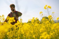 Un homme parlant au téléphone dans un champ de moutarde par une journée ensoleillée — Photo de stock