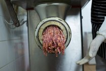 Butcher using machine to minced meat in butcher shop — Stock Photo