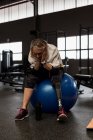 Worried disabled woman sitting on exercise ball in the gym — Stock Photo