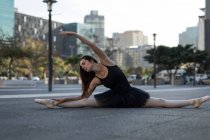 Танцовщица балета, растянувшаяся перед танцами на городской улице — стоковое фото