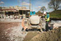 Ingenieur mischt Zement in Betonmischer auf Baustelle — Stockfoto