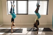 Dos mujeres haciendo ejercicio en hamaca columpio en el gimnasio - foto de stock