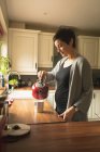 Mujer embarazada preparando café en la cocina en casa - foto de stock