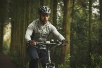 Cyclist in sportswear riding bicycle through forest — Stock Photo