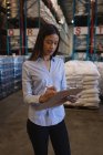 Female supervisor writing on a clipboard in warehouse — Stock Photo