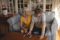 Coppia anziana che utilizza tablet digitale sul divano di casa — Foto stock