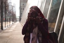 Woman clicking photo with digital camera in city street — Stock Photo