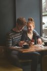 Giovane coppia utilizzando i telefoni cellulari nel caffè — Foto stock