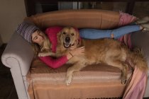 Menina com cão relaxante na sala de estar em casa — Fotografia de Stock