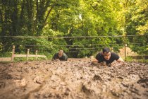 Подходящие мужчины тренируются на полосе препятствий в учебном лагере — стоковое фото
