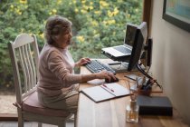 Seniorin benutzt zu Hause einen Desktop-Computer — Stockfoto