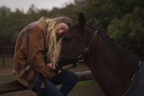 Девочка-подросток, обнимающая лошадь на ранчо — стоковое фото