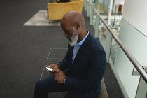 Homme d'affaires utilisant un téléphone portable dans le couloir du bureau — Photo de stock