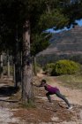 Atleta feminina determinada se exercitando na floresta — Fotografia de Stock