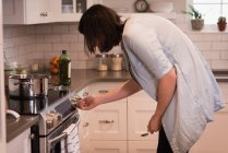 Woman using oven in kitchen at home — Stock Photo