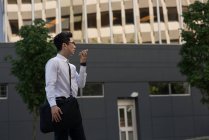 Young man talking on mobile phone while walking on the street — Stock Photo