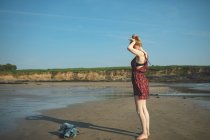 Donna che gioca con la sua ombra sulla spiaggia in una giornata di sole — Foto stock