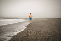 Вид ззаду чоловік біжить на березі на пляжі — стокове фото