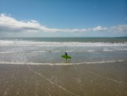 Vista de ángulo alto de Surfista con tabla de surf caminando en la playa - foto de stock