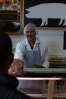 Carniceiro feliz vendendo carne no açougue — Fotografia de Stock