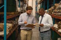 Male managers discussing over clipboard in warehouse — Stock Photo