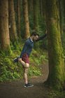 Hombre en forma haciendo ejercicio de estiramiento en el bosque - foto de stock