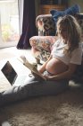 Беременная женщина читает книгу в гостиной дома — стоковое фото