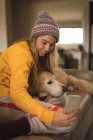 Дівчина бере селфі з собакою у вітальні вдома — стокове фото