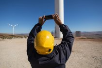 Engenheiro fotografando um moinho de vento em um parque eólico — Fotografia de Stock