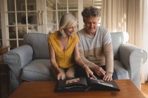 Senior couple looking at photo album at home — Stock Photo