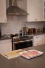 Carne em uma bandeja na bancada da cozinha em casa — Fotografia de Stock