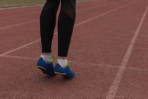 Atleta femenina calentándose en pista de atletismo - foto de stock