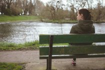 Schöne Frau entspannt sich auf Bank in der Nähe des Flusses — Stockfoto