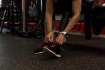 Низький розділ жінки з обмеженими можливостями зав'язування шнурків у спортзалі — стокове фото