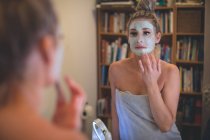 Жінка застосовує крем для обличчя у ванній вдома — стокове фото