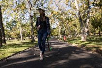 Женщина, гуляющая в парке со скейтбордом — стоковое фото