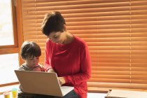 Mãe e filho sentados com um laptop em casa — Fotografia de Stock