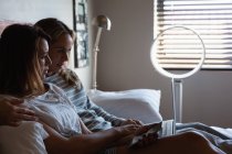 Lesbisches Paar benutzt Laptop und Handy im Schlafzimmer zu Hause — Stockfoto