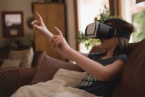 Fille en utilisant un casque de réalité virtuelle dans le salon à la maison — Photo de stock