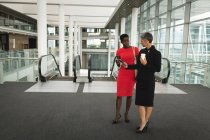 Дві бізнес-леді обговорюють мобільний телефон в офісі — стокове фото
