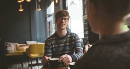 Jovem sorridente conversando com mulher no café — Fotografia de Stock