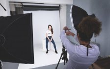 Женщина-фотограф щелкает фотографиями модели в фотостудии — стоковое фото