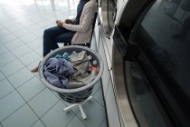 Vista ad alto angolo della donna che usa il suo telefono mentre aspetta in lavanderia — Foto stock