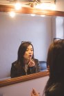 Model applying lipstick in changing room at photo studio — Stock Photo