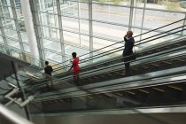 Drei Geschäftsleute auf einer Rolltreppe im Büro — Stockfoto