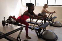 Duas mulheres se exercitando na máquina de alongamento no estúdio de fitness — Fotografia de Stock