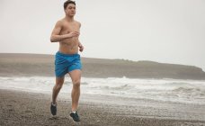 Giovane uomo che fa jogging sulla spiaggia — Foto stock