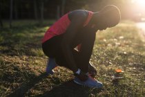 Female athlete tying her shoe lace in the forest — Stock Photo