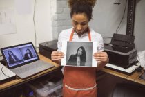 Молода жінка-фотограф, що показує фотографії в фотостудії — стокове фото